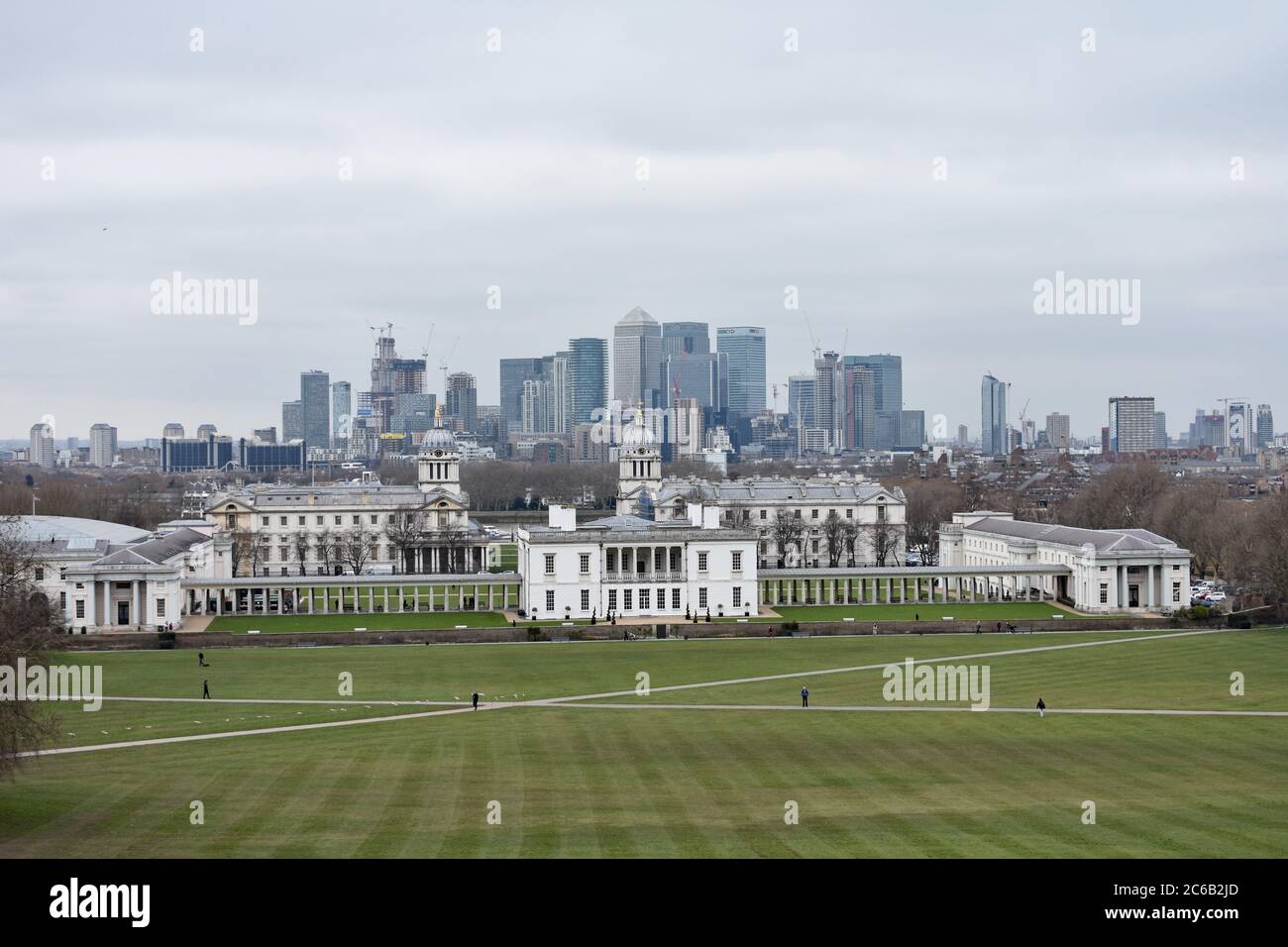 The Old Royal Navy College and Queens House from the hill in Greenwich Park.  Canary Wharf business district is seen behind, across the River Thames. Stock Photo