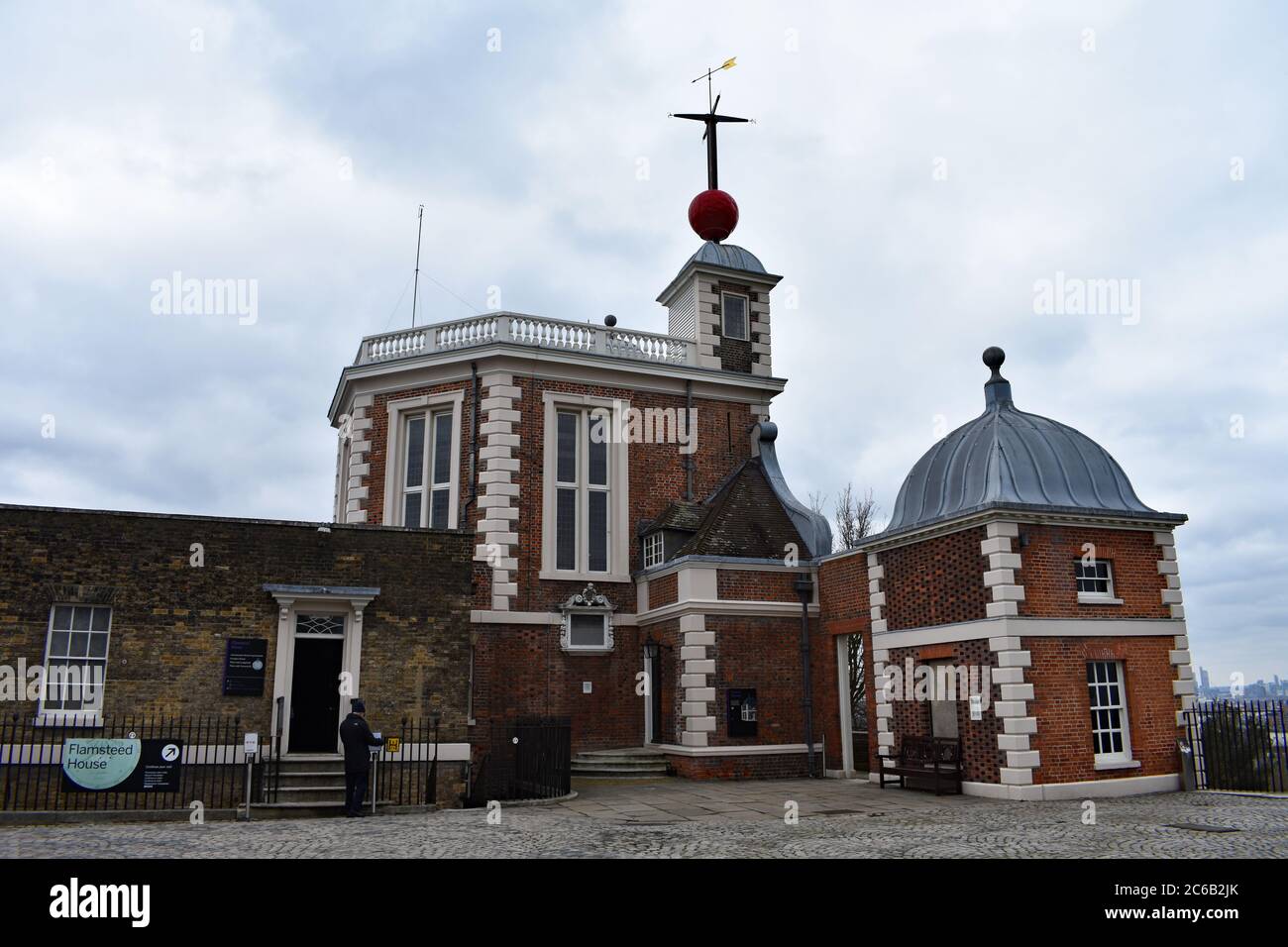 A visitor about to enter Flamsteed House at the Royal Observatory in Greenwich Park. A red time ball and weather vane above the Octagon Room. Stock Photo