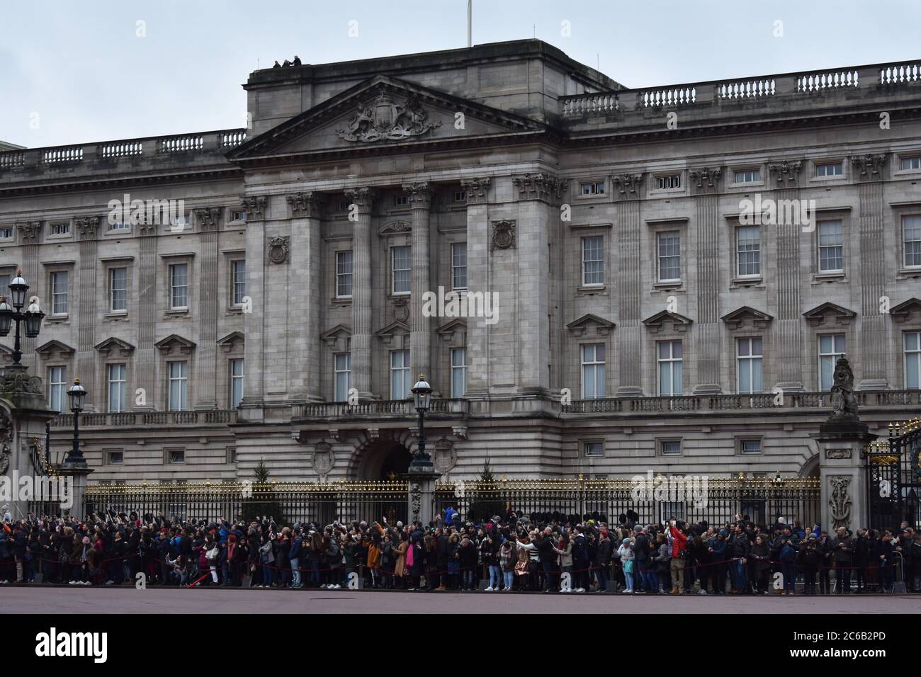 Crowds gather outside Buckingham Palace for the Changing Of The Guard Ceremony.  The imposing east facade and balcony for royal appearances. Stock Photo