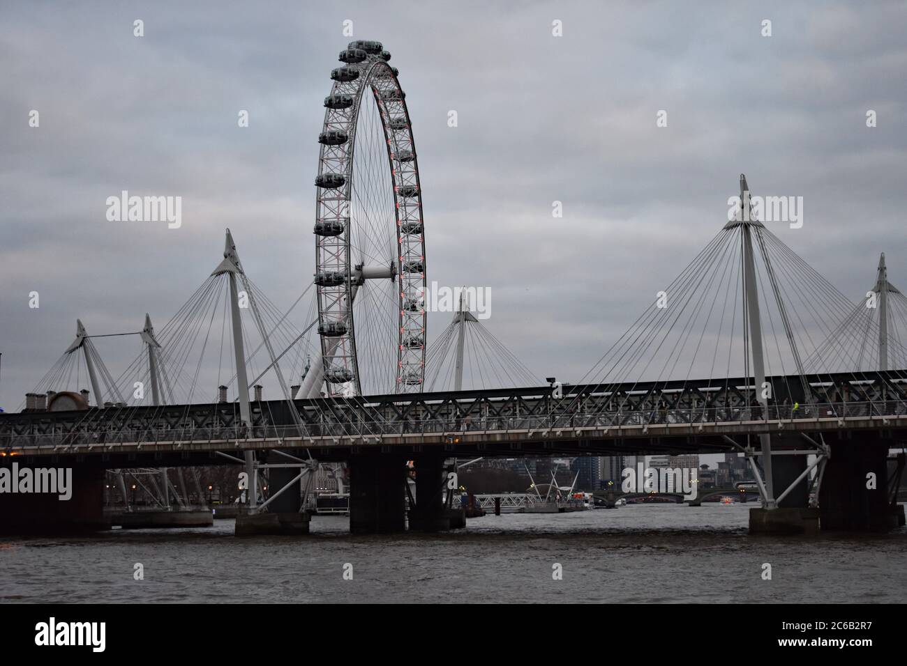 Golden Jubilee Bridge and Hungerford Bridge leading from Charing Cross over the River Thames in London. The London Eye appears above the bridges.  UK Stock Photo
