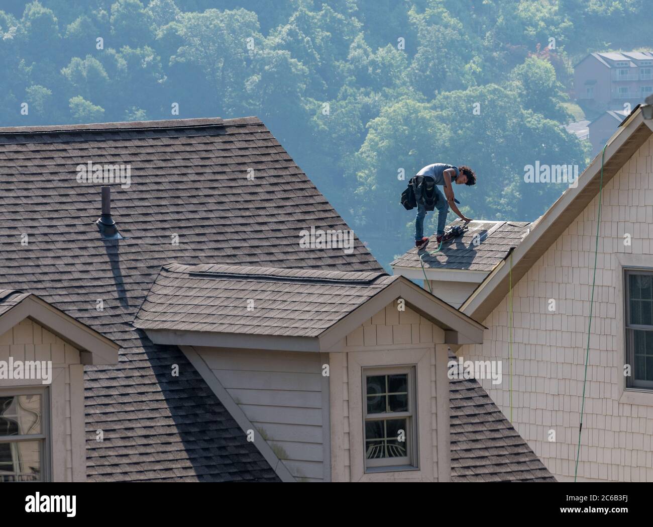 WV 8 July 2020 Young roofing contractor replacing the old shingles on a townhouse