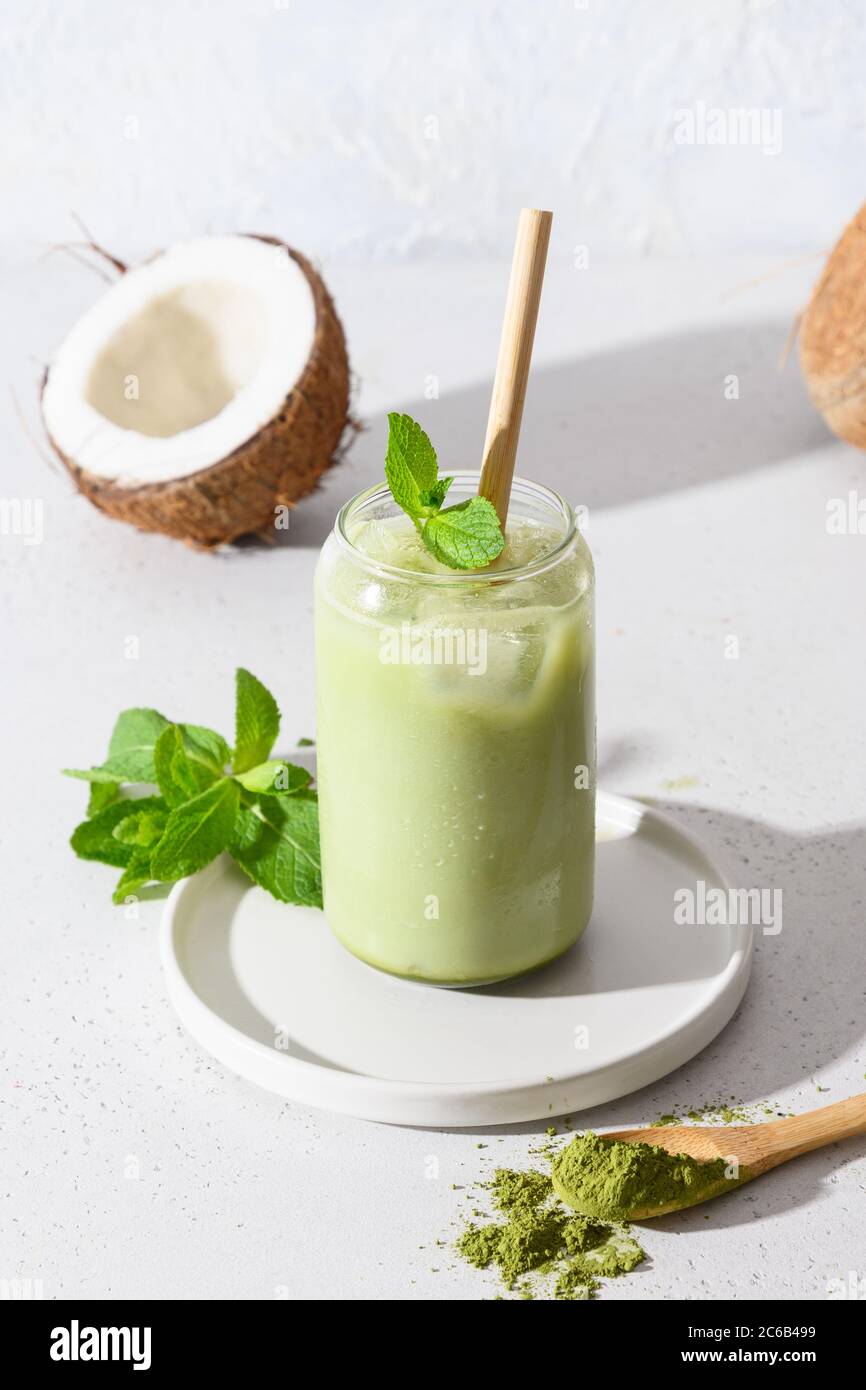 Iced latte green matcha tea with coconut milk garnish mint on white background. Stock Photo