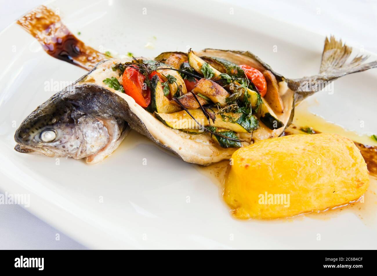 Baked trout on a plate. Delicious fish meal filled with vegetable ...
