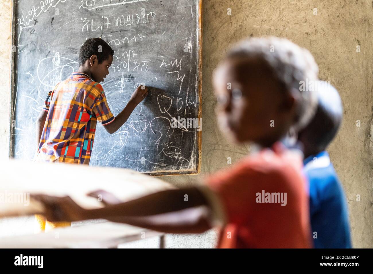 Young boy writing on blackboard at school, Melabday, Asso Bhole, Danakil Depression, Afar Region, Ethiopia, Africa Stock Photo