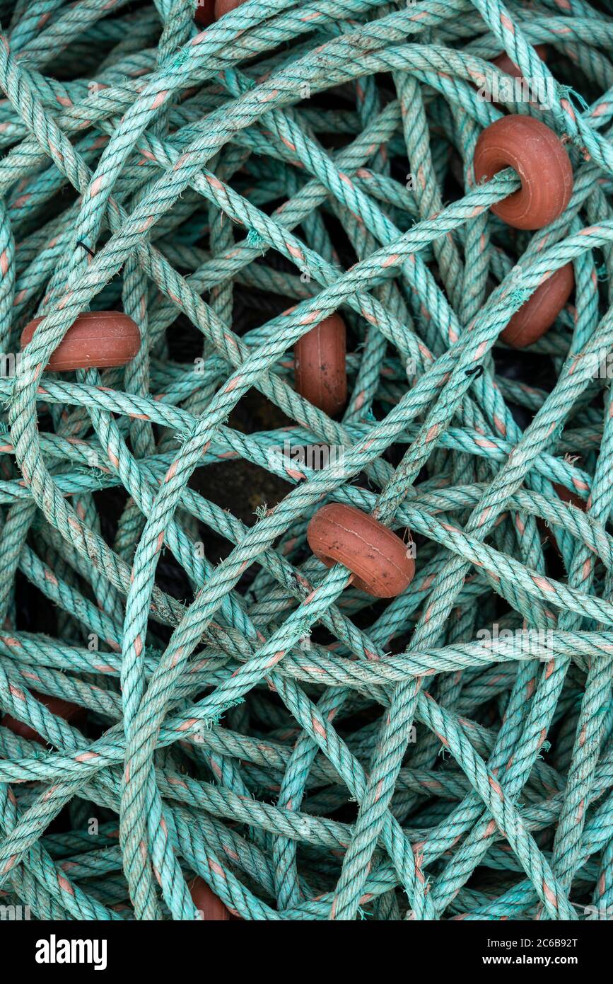 Overhead view of a pile of green fishing rope with orange buoys Stock Photo