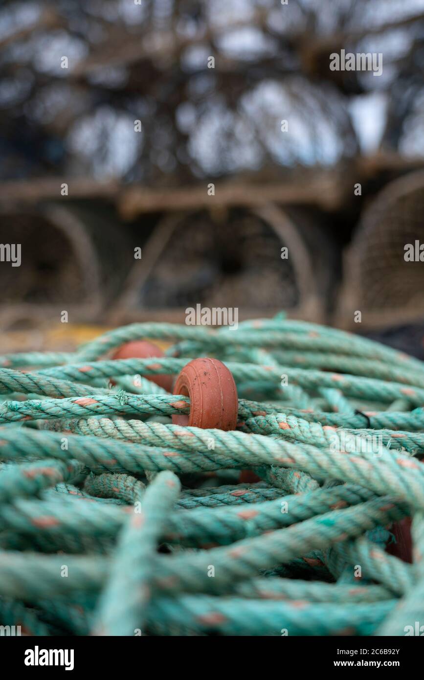 Green fishing rope with out of focus lobster pots in the background Stock Photo