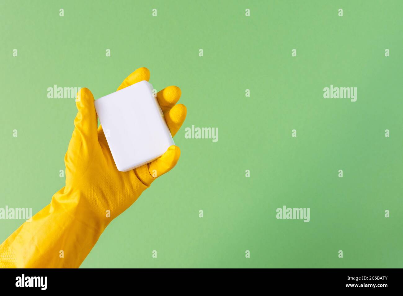 Hand in a yellow rubber glove with soap on a green background Stock ...