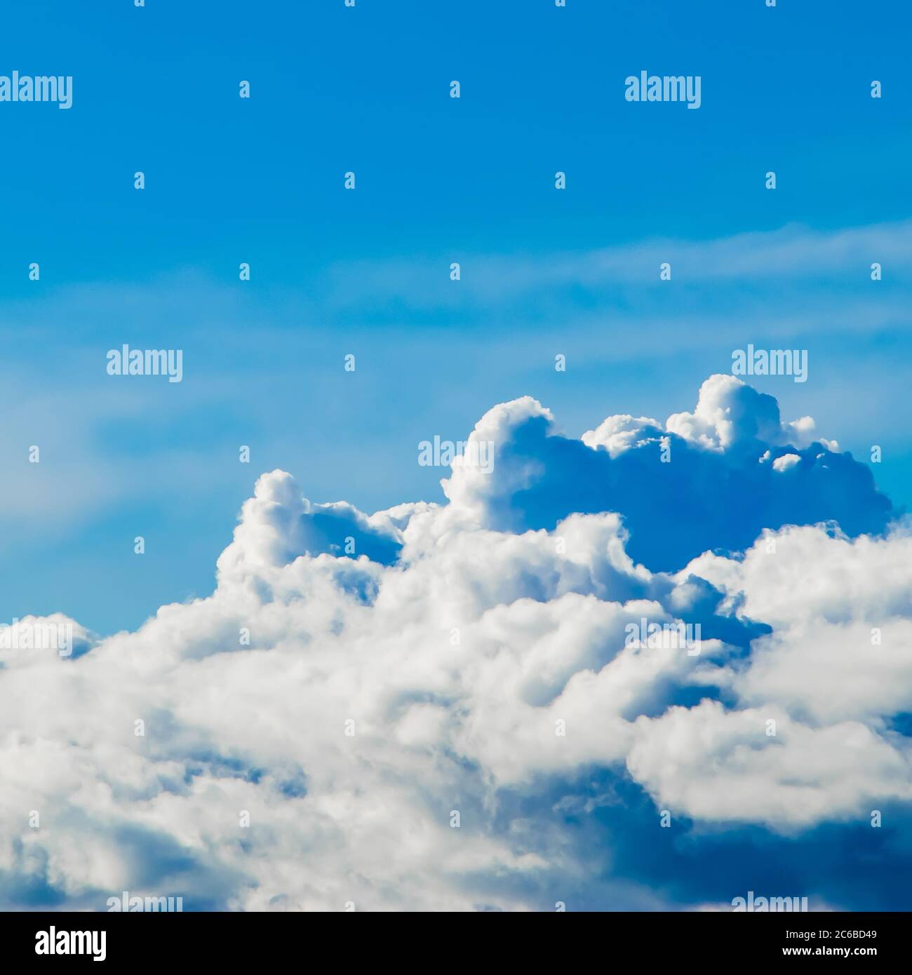 White fluffy cumulus clouds on the clear blue sky in the sunshine ...