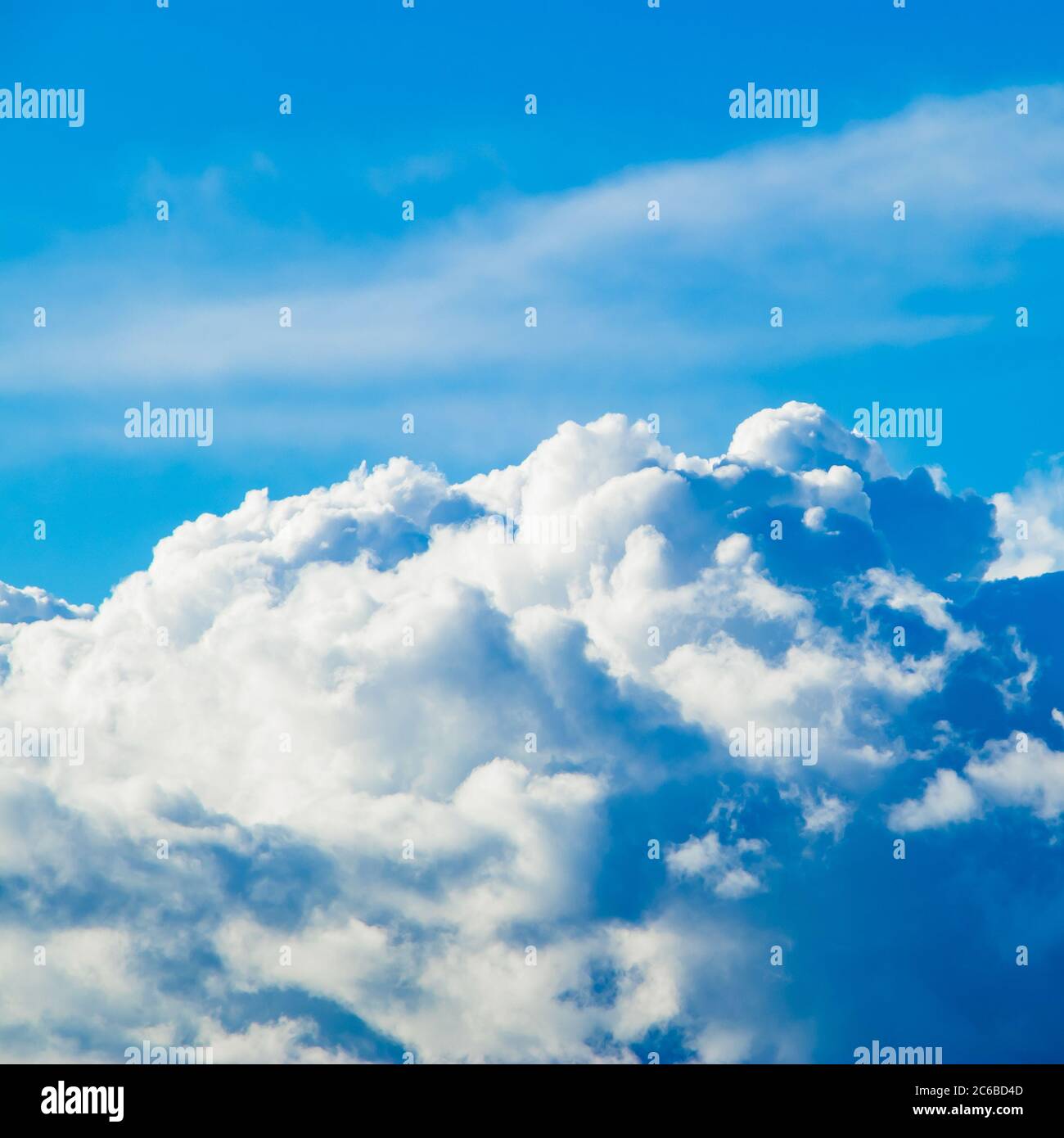 White fluffy cumulus clouds on the clear blue sky in the sunshine. Top view from the plane. Background for design. Square photo Stock Photo