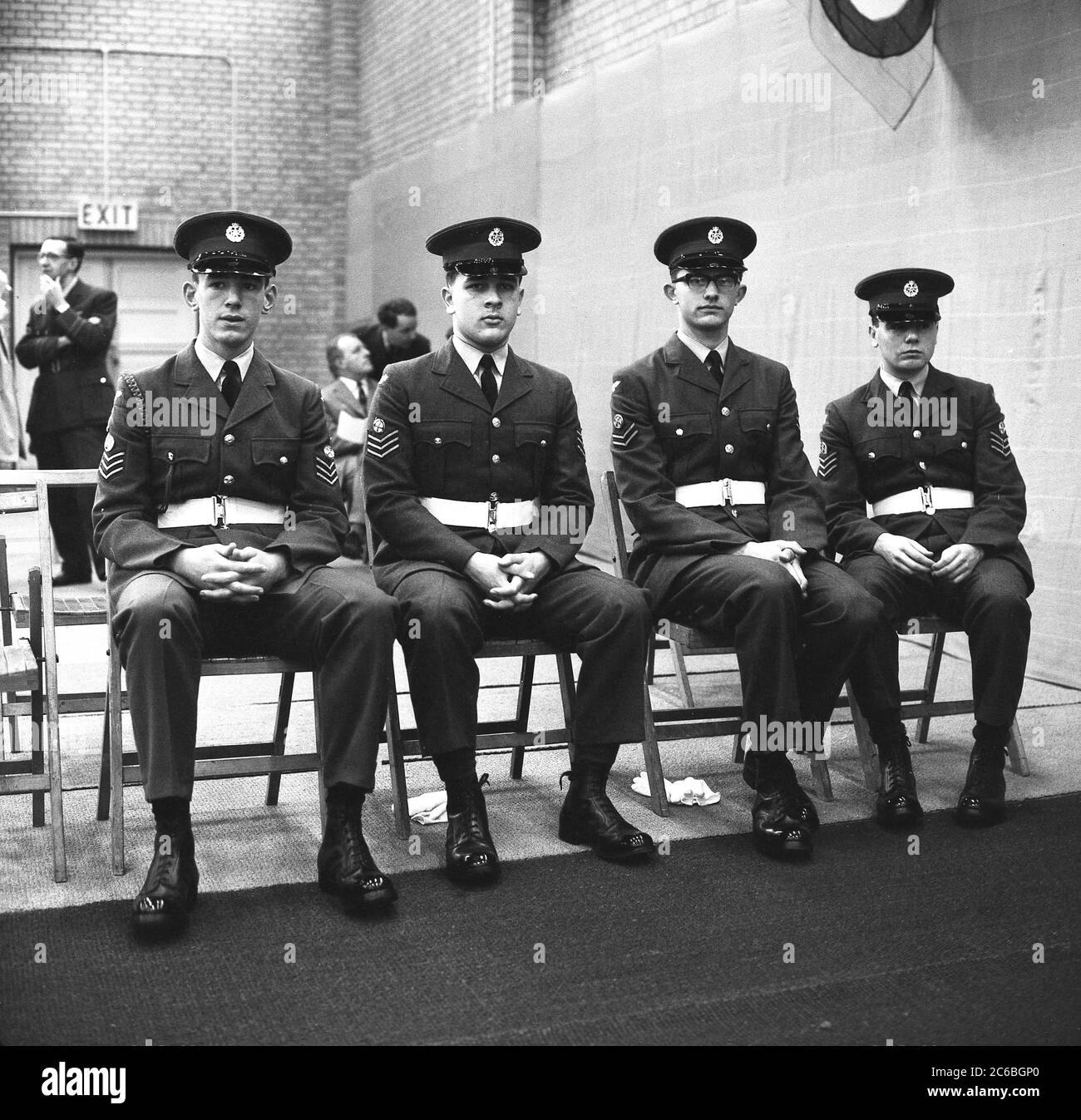 1960s, historical, four young male RAF apprentices at RAF Halton, Buckinghamshire, England, UK sitting together in a hall in their uniforms and polished boots following their graduation. At the end of WW1, the British government purchased the estate from Alfred de Rothschild to establish a school of technical training for RAF aircraft apprentices. Stock Photo