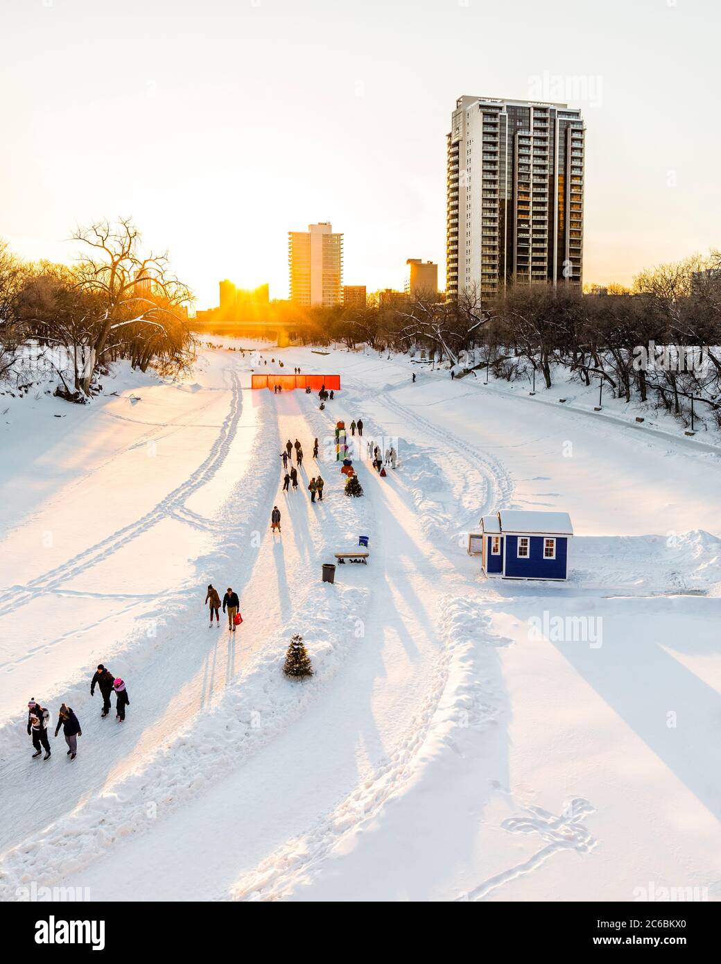 Ice skating on the Assiniboine River Trail at sunset, part of the Red River Mutual Trail, The Forks, Winnipeg, Manitoba, Canada. Stock Photo