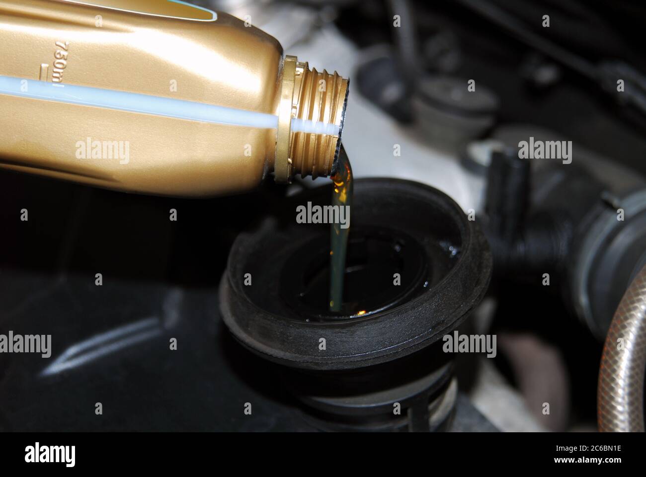 Adding Oil to a Car, man's hand holding a bowl of motor oil and poured into the engine, From