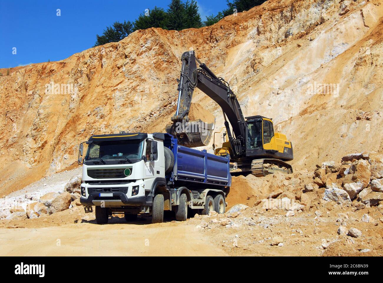 Yellow excavator, dredge, Yellow excavator loading rocks into a truck ...