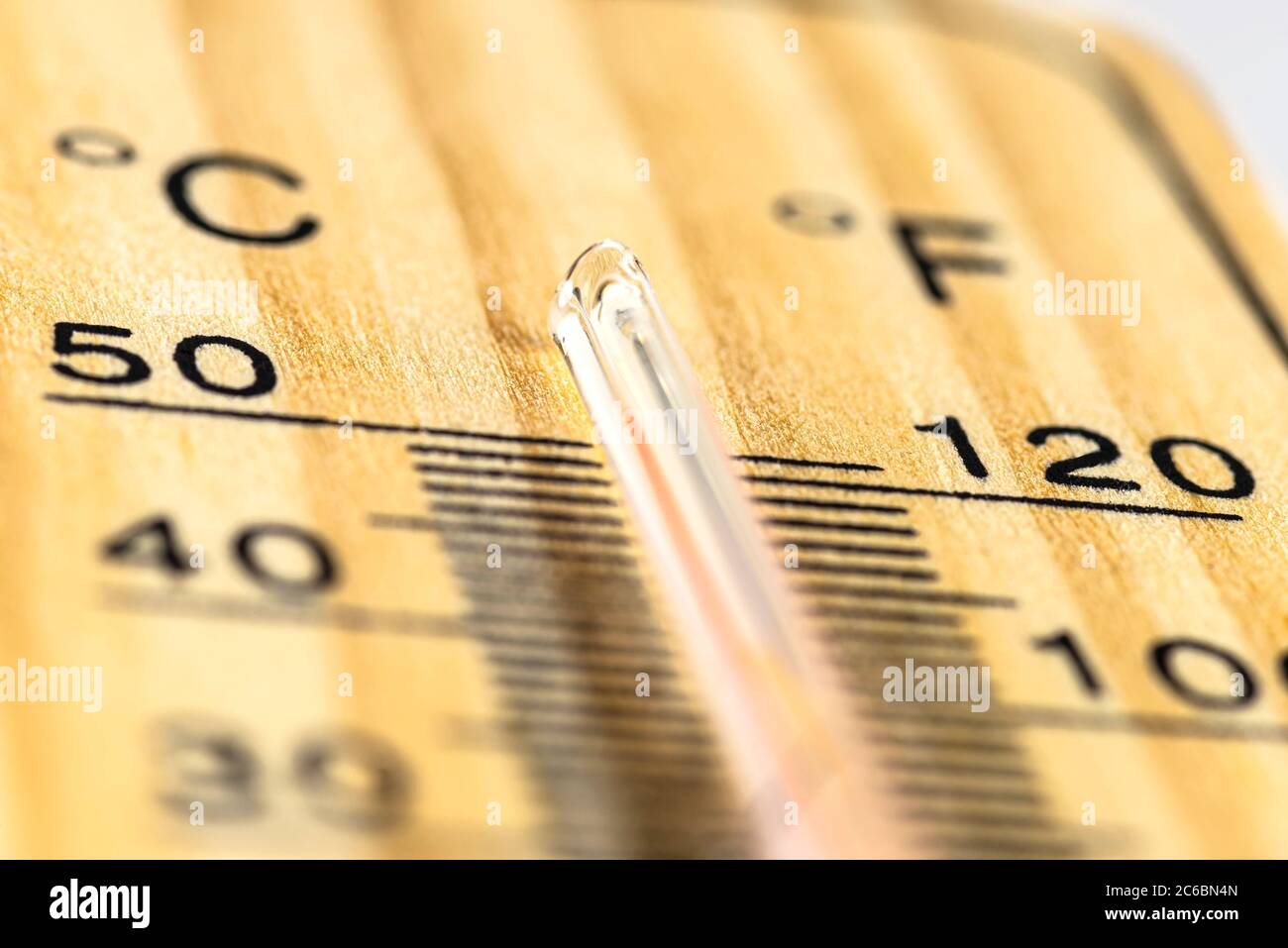 A macro shot of a classic wooden thermometer showing a temperature over 50 degrees Celsius, 122 degrees Fahrenheit. Stock Photo