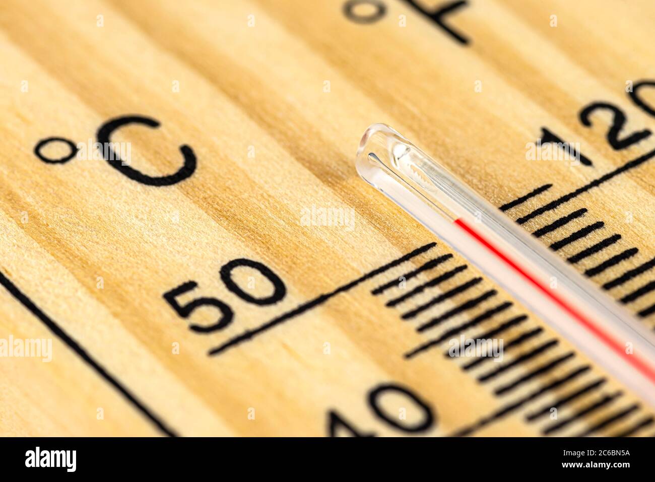 A macro shot of a classic wooden thermometer showing a temperature over 50 degrees Celsius, 122 degrees Fahrenheit. Stock Photo