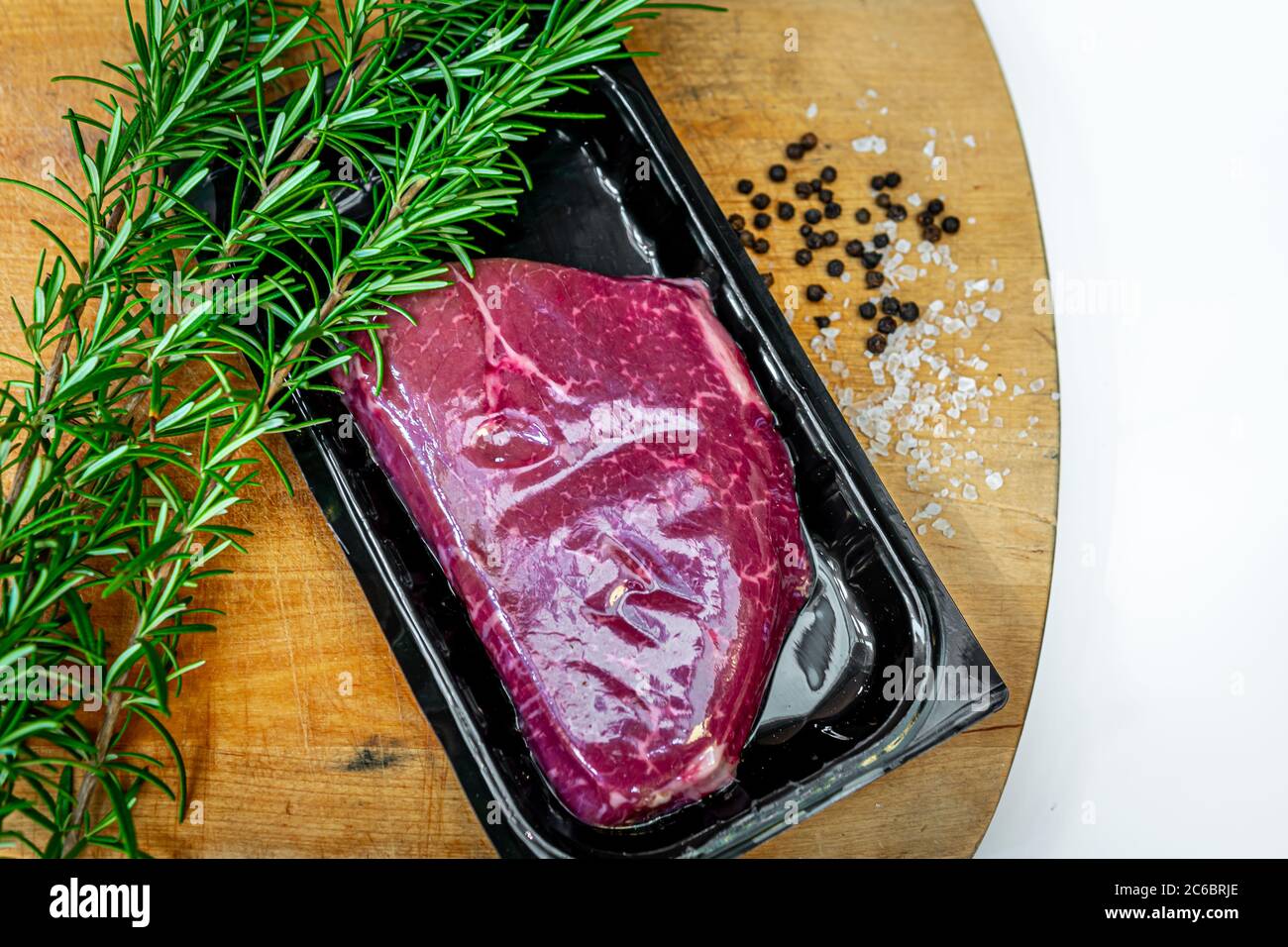 Beef steak in airtight skin packaging and spices on wooden chopping board Stock Photo