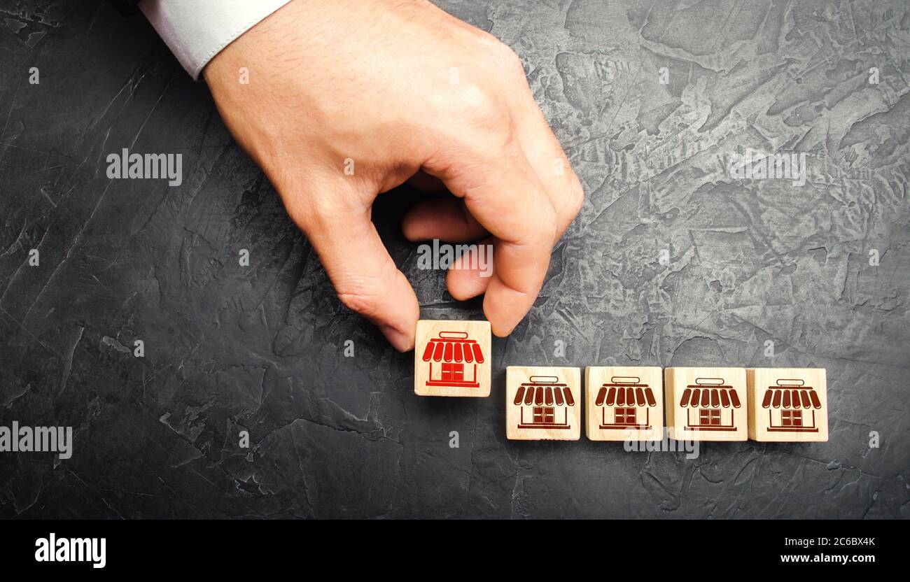 Man Adding a block with a store icon to others. Franchise commercial