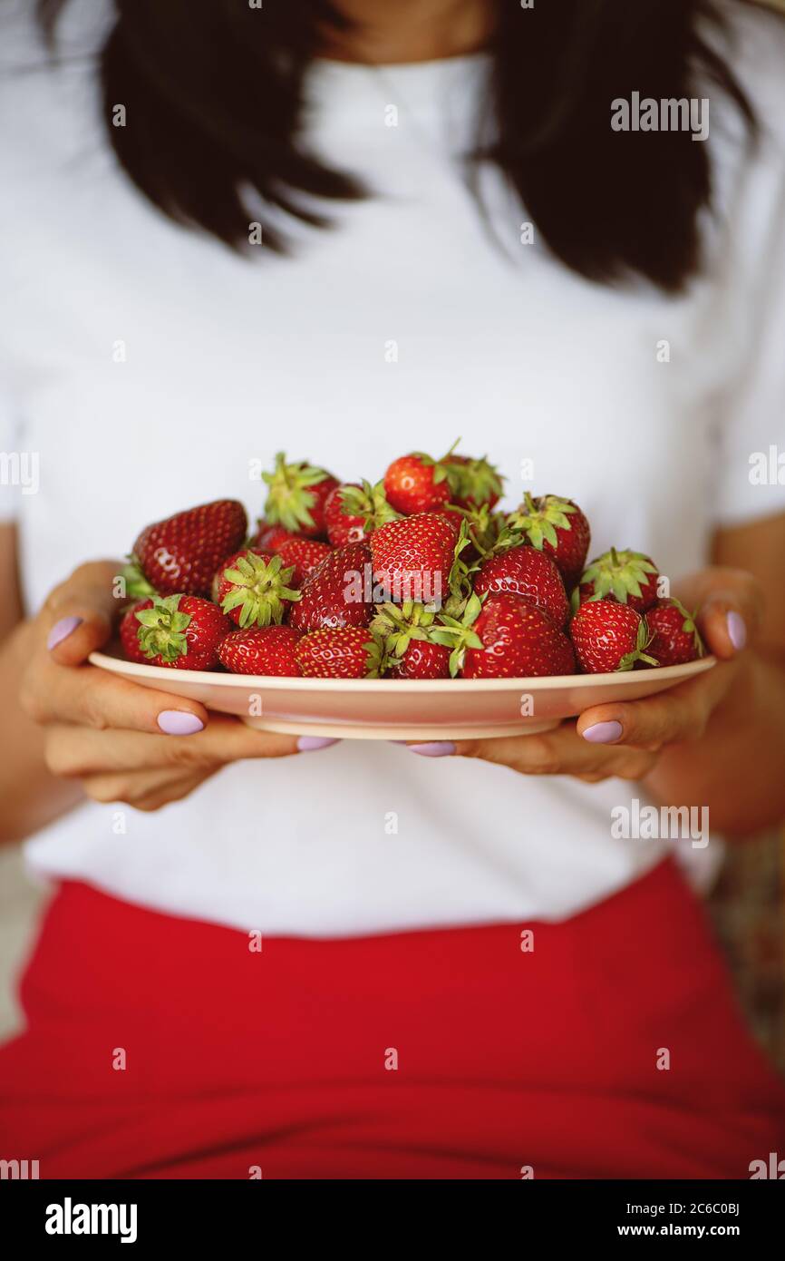Woman holding strawberries in a plate. Summer food concept. Stock Photo