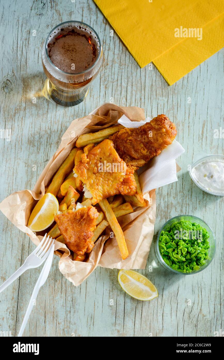Deep fried fish and chips in combination with lemon slices, green peas