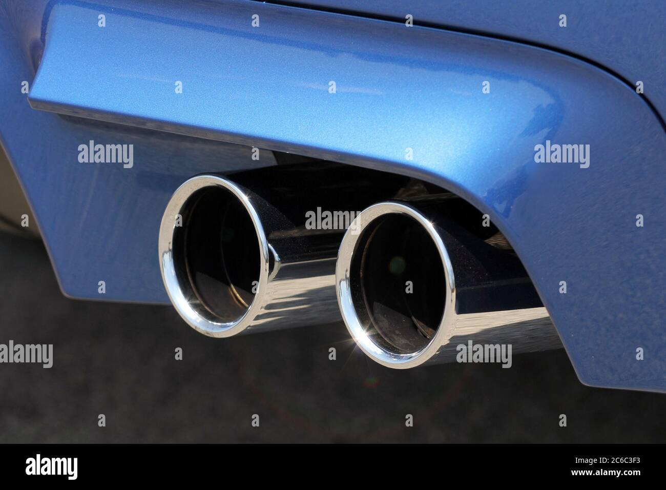 Exhaust pipe system. Tailpipe sports car. Close up of tailpipe on blue