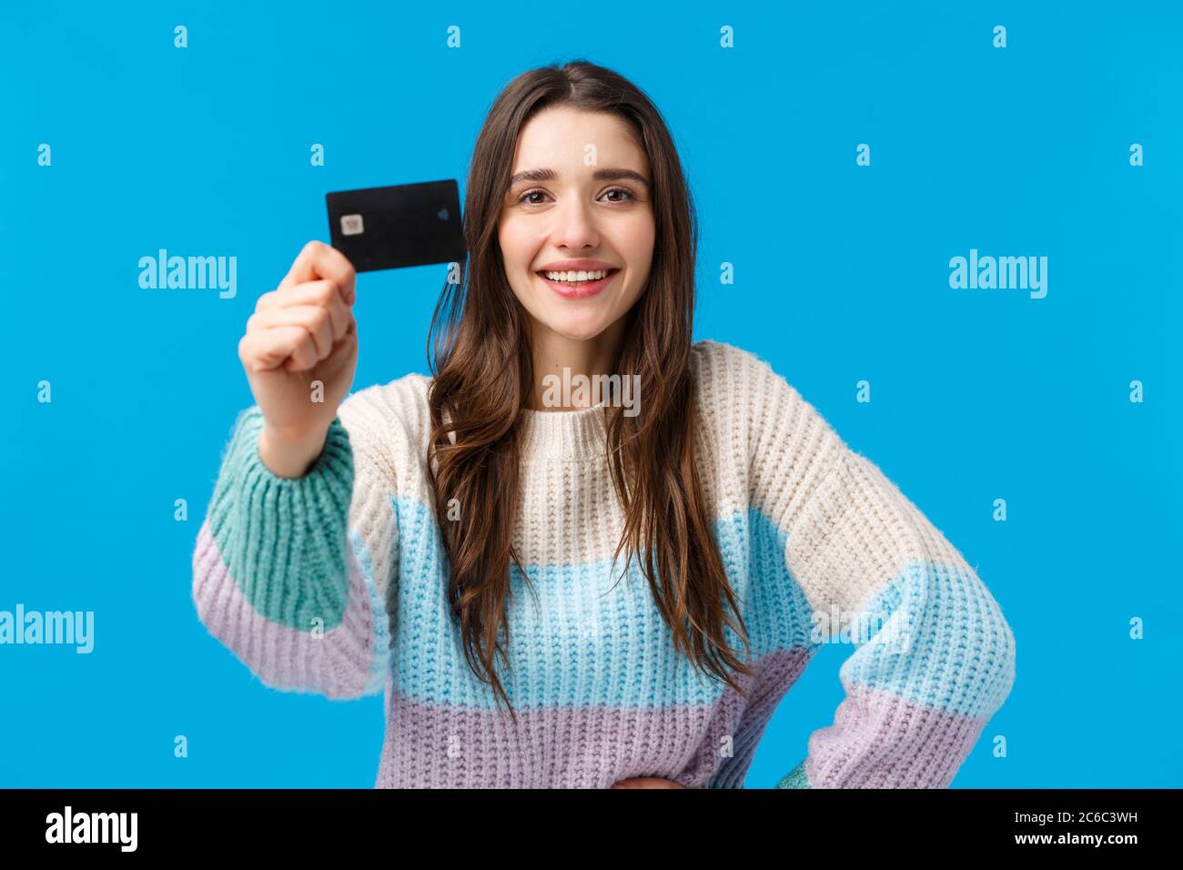 Best bank for young generation. Attractive pleased charismatic young woman in winter sweater, showing credit card and smiling satisfied, recommend Stock Photo
