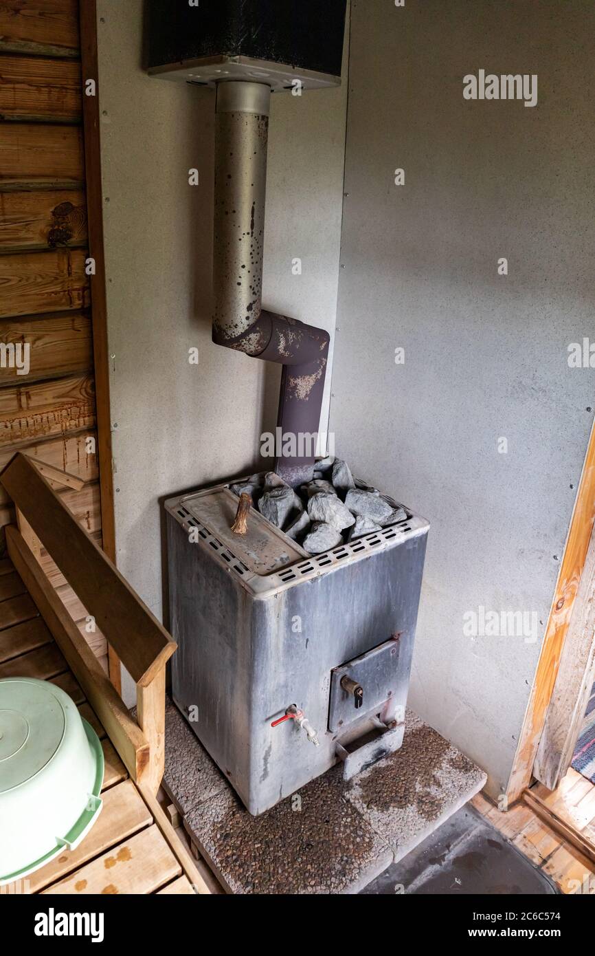Traditional old wood burning sauna heater stove with built-in water heater in a Finnish sauna Stock Photo
