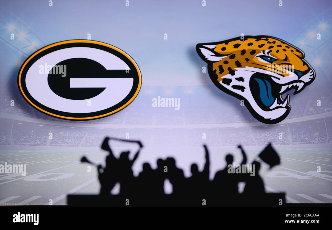 Green Bay Packers vs. Jacksonville Jaguars. Fans support on NFL Game. Silhouette of supporters, big screen with two rivals in background. Stock Photo