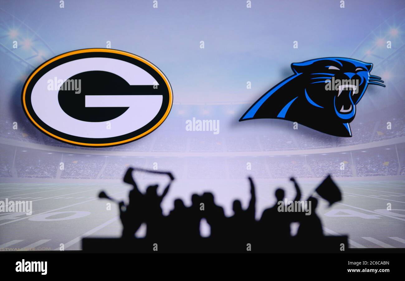 Green Bay Packers vs. Carolina Panthers. Fans support on NFL Game. Silhouette of supporters, big screen with two rivals in background. Stock Photo