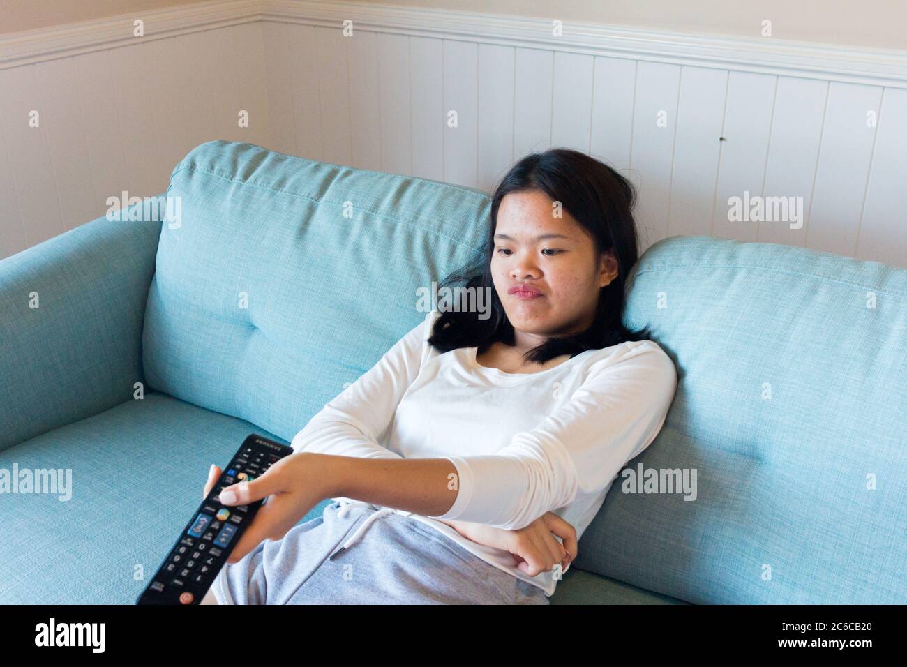 Asian teenage girl sitting on sofa watch television Stock Photo - Alamy