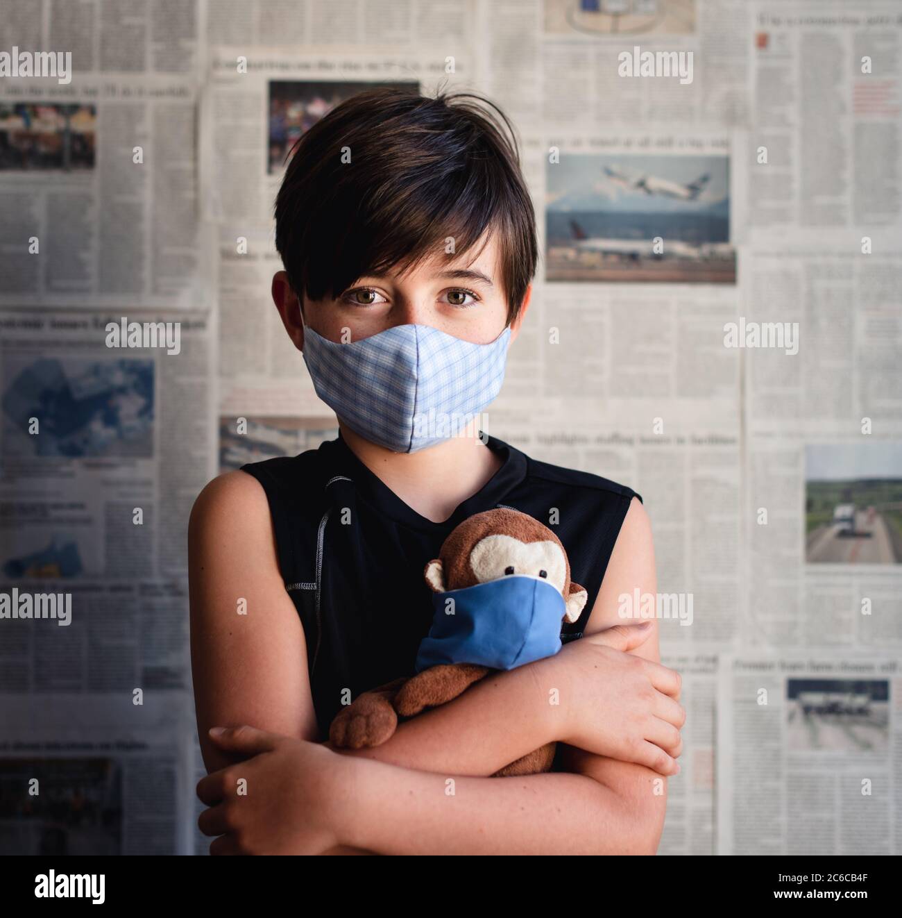Young Boy Wearing Mask Holding Toy Monkey With Newspaper Backdrop Stock Photo Alamy