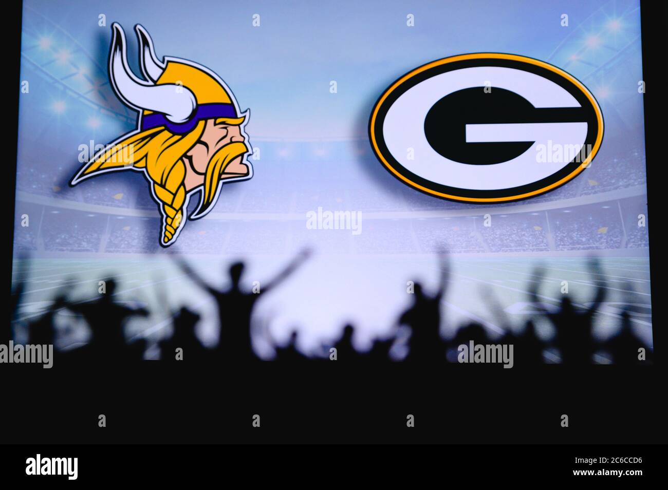 Minnesota Vikings vs. Green Bay Packers. Fans support on NFL Game. Silhouette of supporters, big screen with two rivals in background. Stock Photo