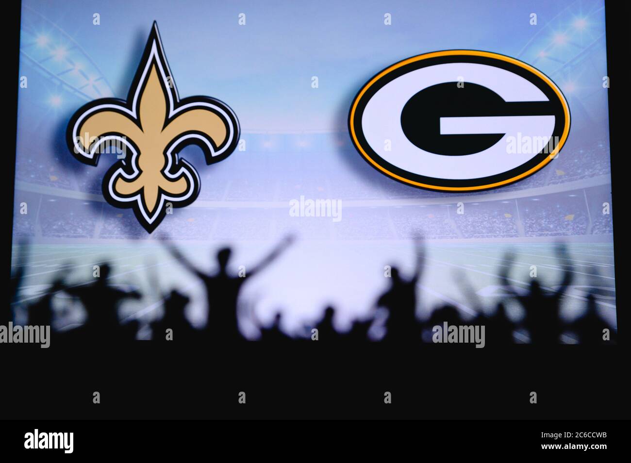 New Orleans Saints vs. Green Bay Packers. Fans support on NFL Game. Silhouette of supporters, big screen with two rivals in background. Stock Photo