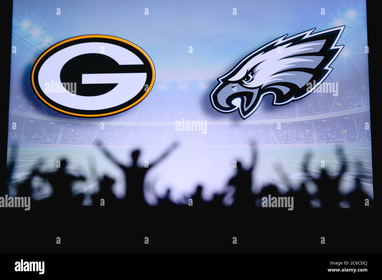 Green Bay Packers vs. Philadelphia Eagles. Fans support on NFL Game. Silhouette of supporters, big screen with two rivals in background. Stock Photo