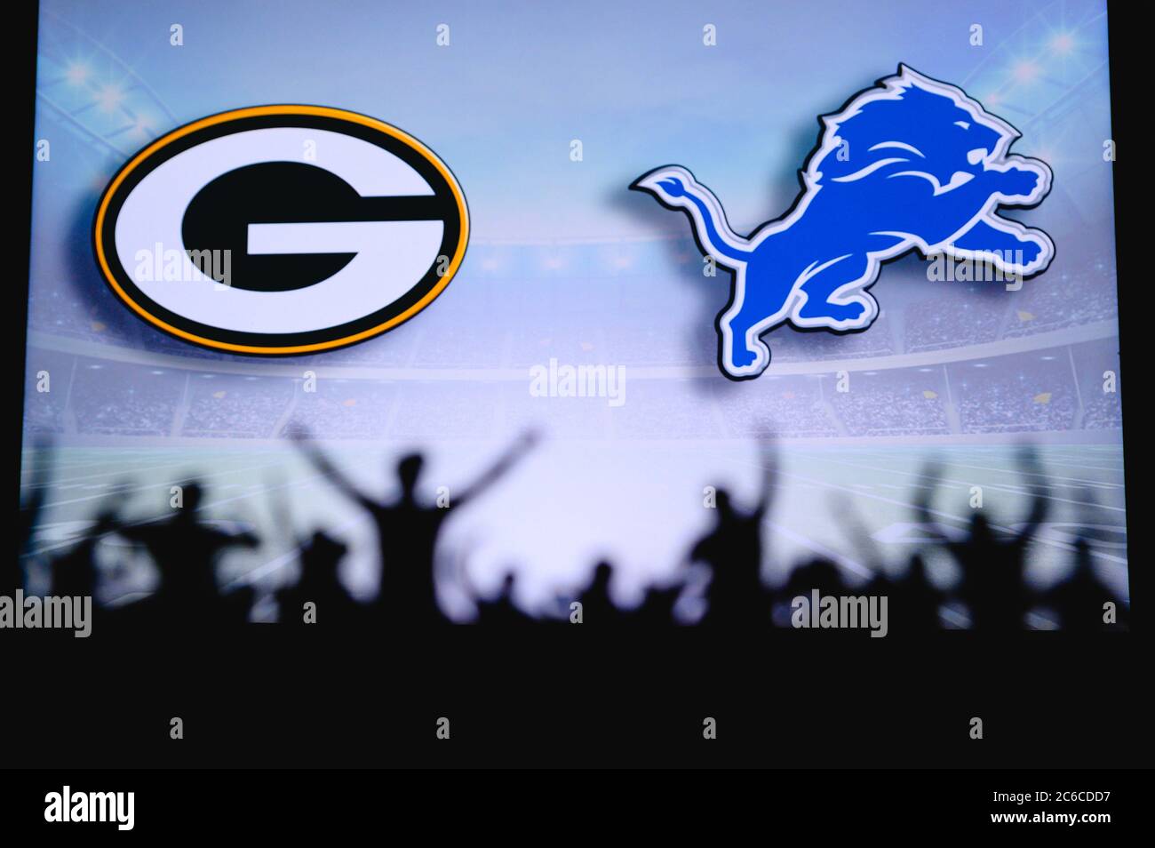 Green Bay Packers vs. Detroit Lions. Fans support on NFL Game. Silhouette of supporters, big screen with two rivals in background. Stock Photo