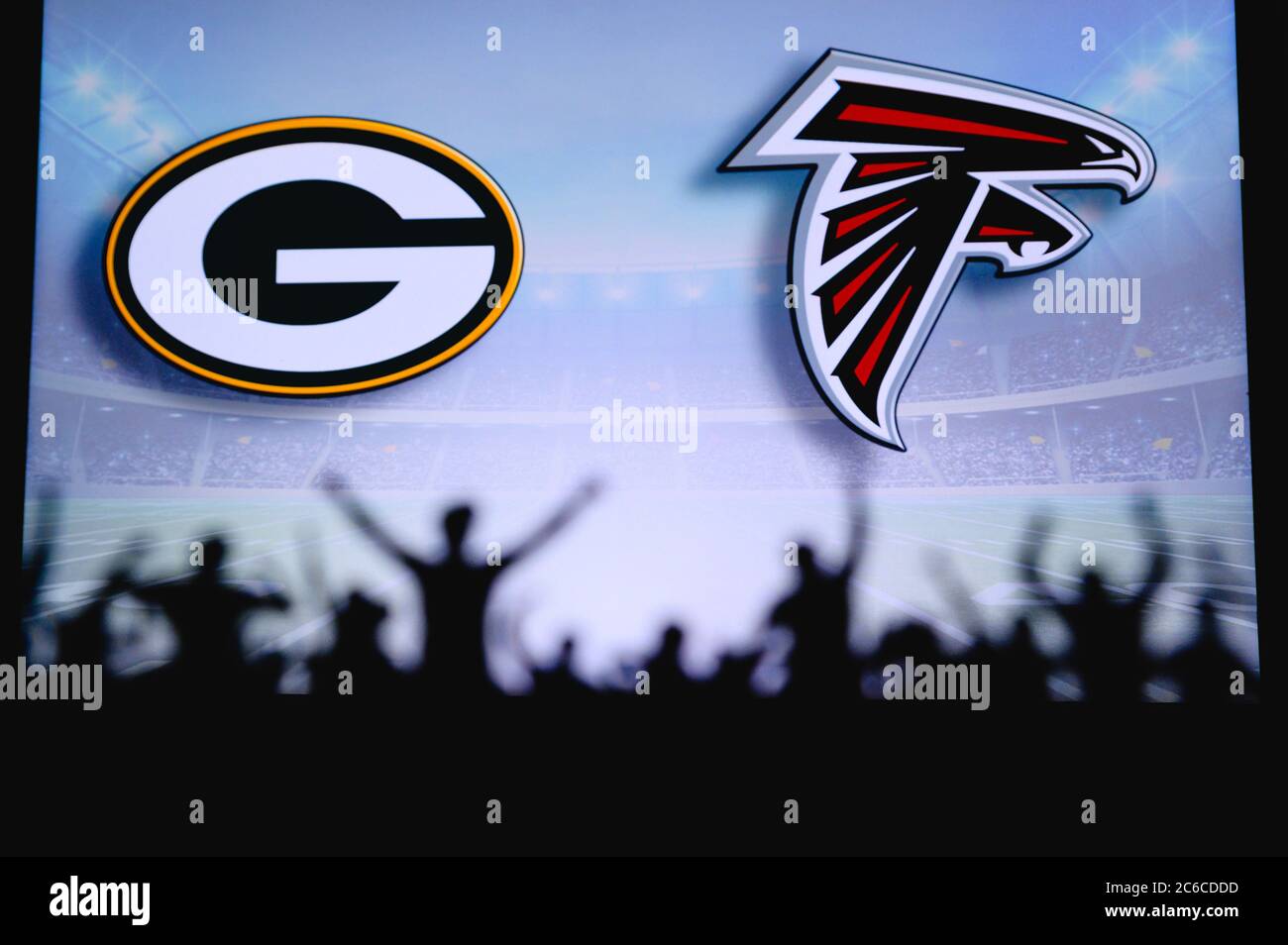 Green Bay Packers vs. Atlanta Falcons. Fans support on NFL Game. Silhouette of supporters, big screen with two rivals in background. Stock Photo