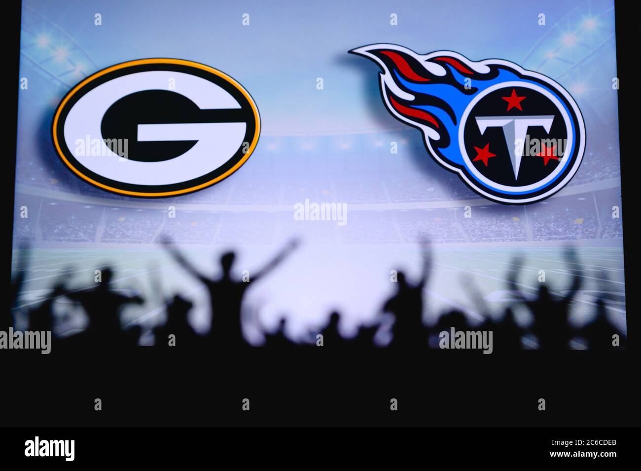 Green Bay Packers vs. Tennessee Titans. Fans support on NFL Game. Silhouette of supporters, big screen with two rivals in background. Stock Photo