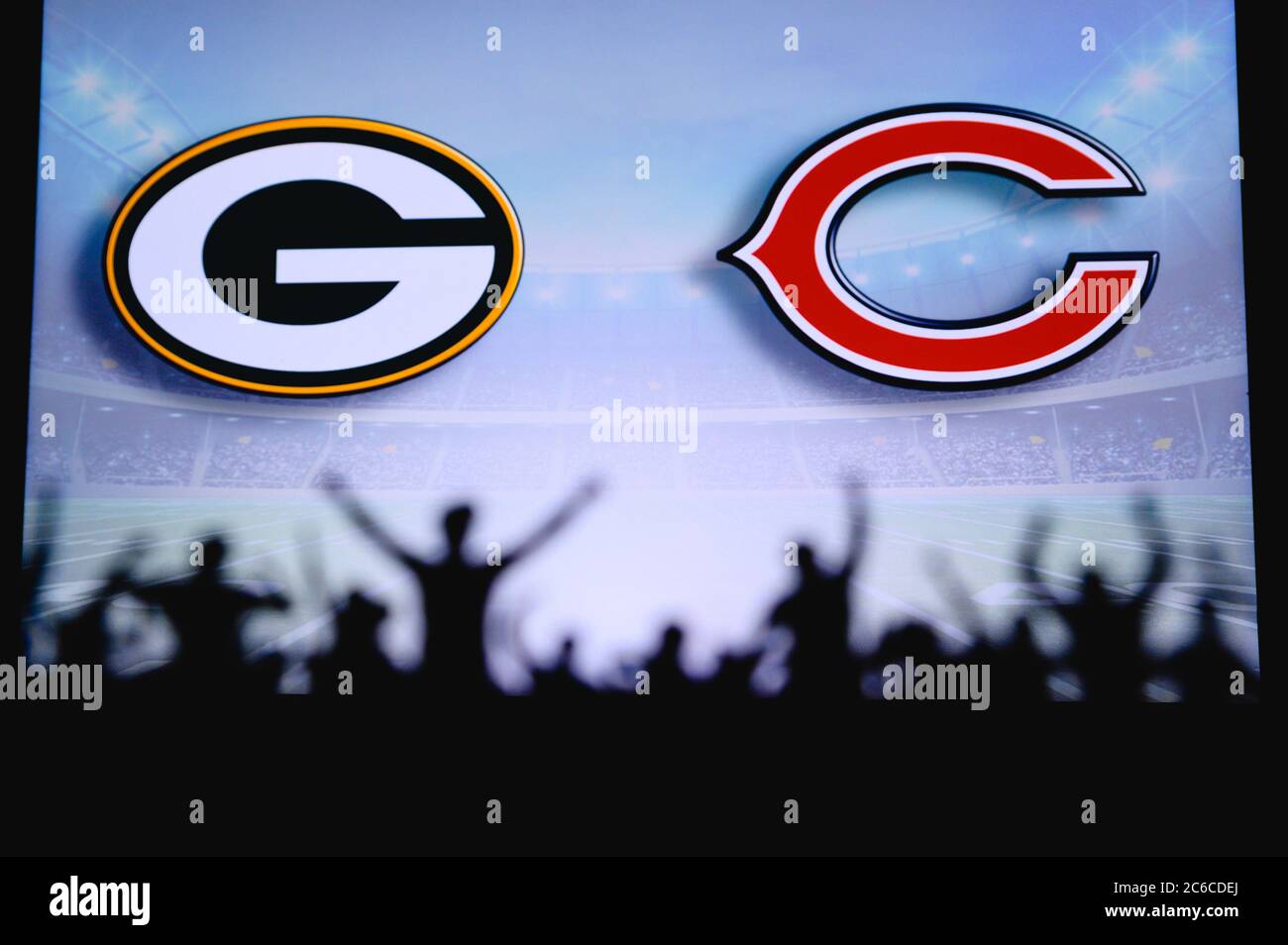 Green Bay Packers vs. Chicago Bears. Fans support on NFL Game. Silhouette of supporters, big screen with two rivals in background. Stock Photo