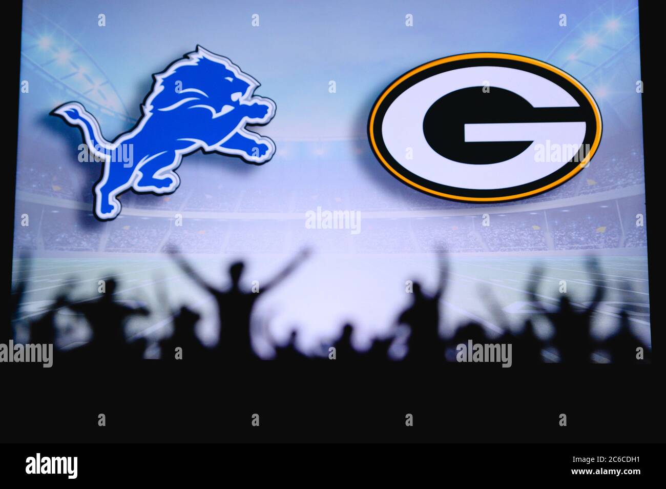 Detroit Lions vs. Green Bay Packers. Fans support on NFL Game. Silhouette of supporters, big screen with two rivals in background. Stock Photo