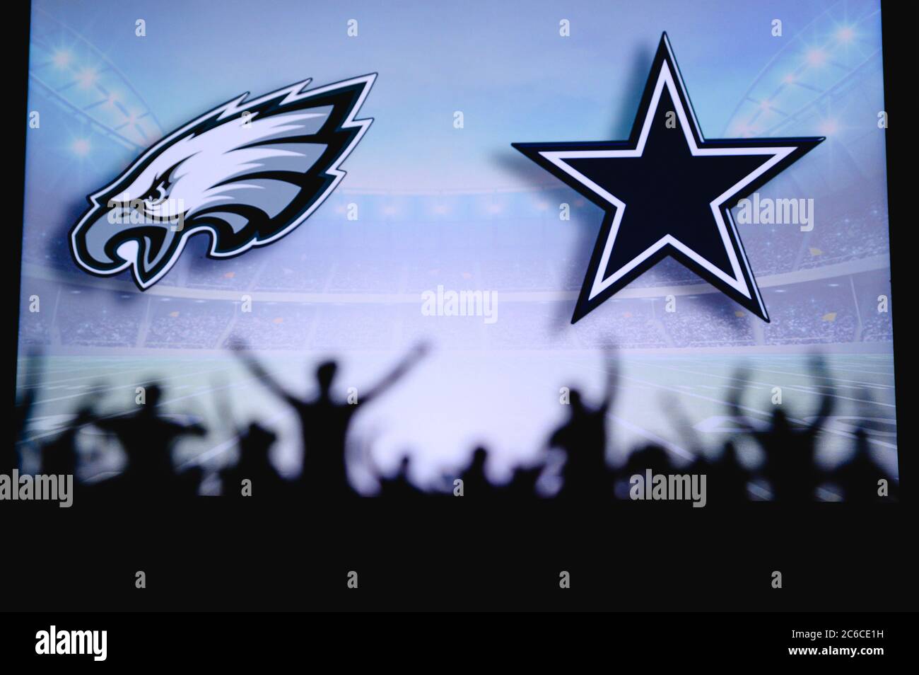 Philadelphia Eagles vs. Dallas Cowboys. Fans support on NFL Game. Silhouette of supporters, big screen with two rivals in background. Stock Photo