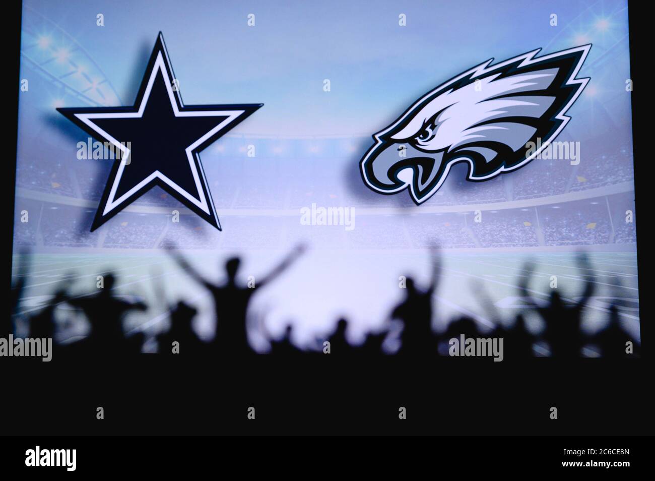 Dallas Cowboys vs. Philadelphia Eagles. Fans support on NFL Game. Silhouette of supporters, big screen with two rivals in background. Stock Photo