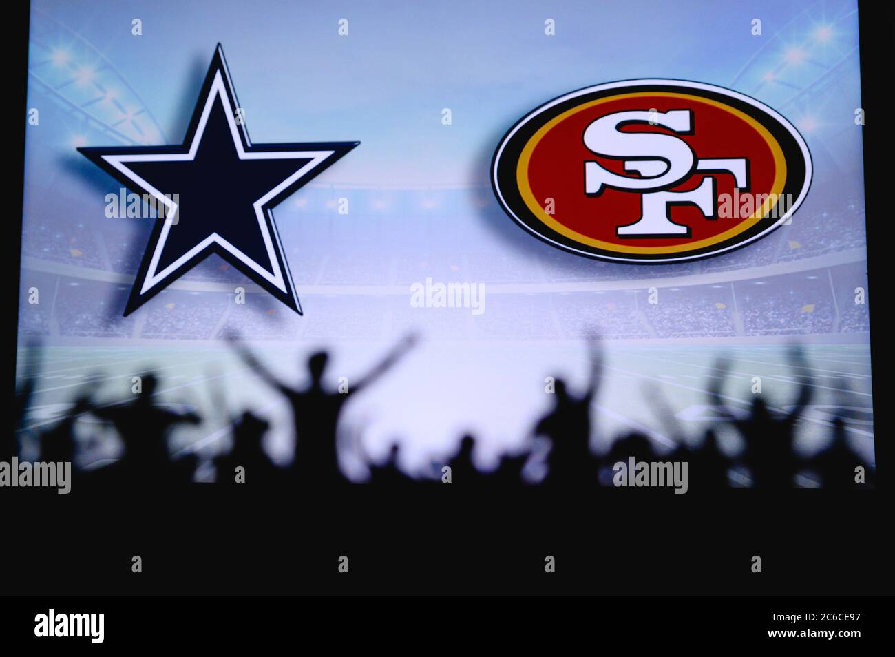 Dallas Cowboys vs. San Francisco 49ers. Fans support on NFL Game. Silhouette of supporters, big screen with two rivals in background. Stock Photo