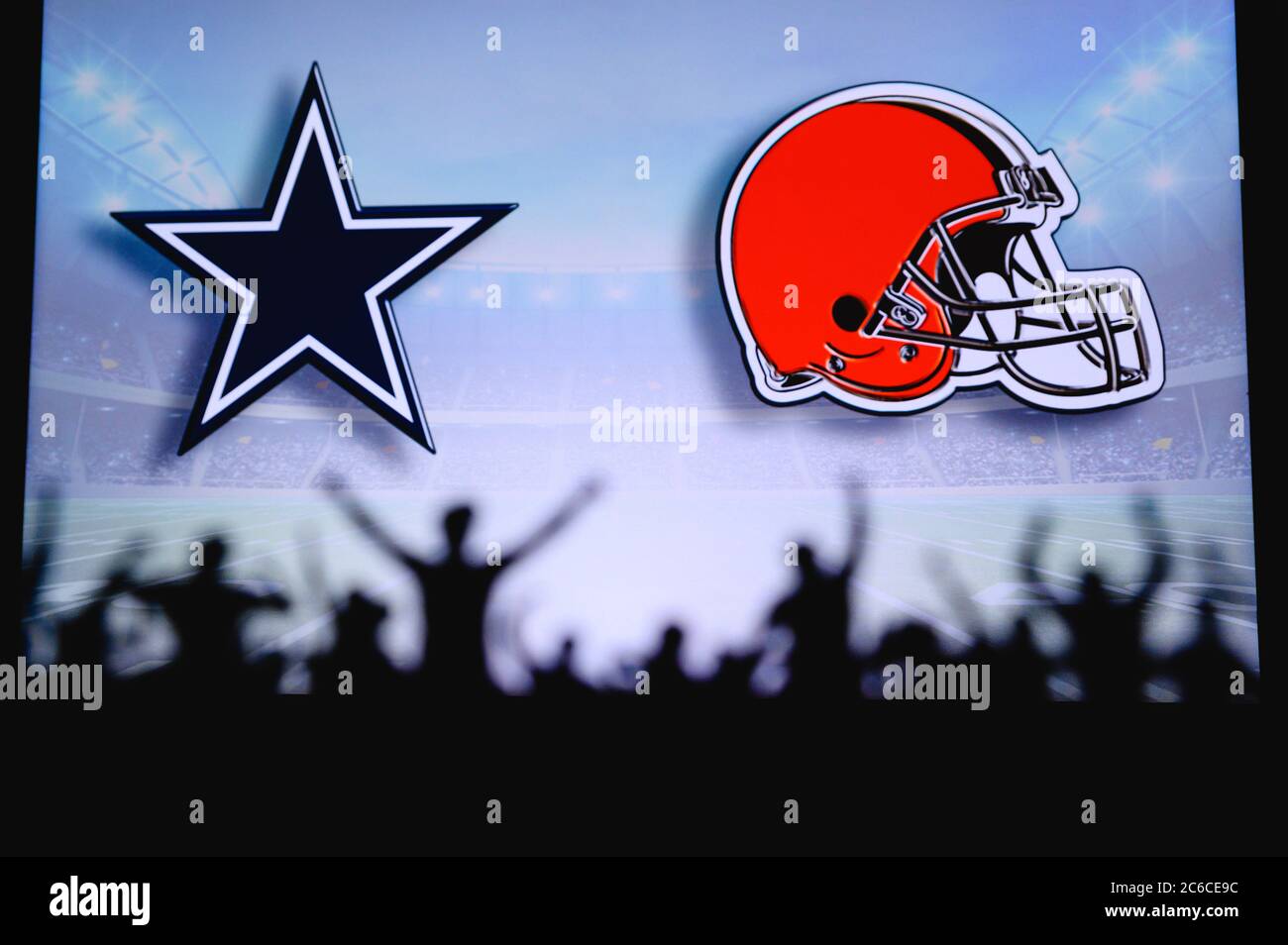 Dallas Cowboys vs. Cleveland Browns. Fans support on NFL Game. Silhouette of supporters, big screen with two rivals in background. Stock Photo