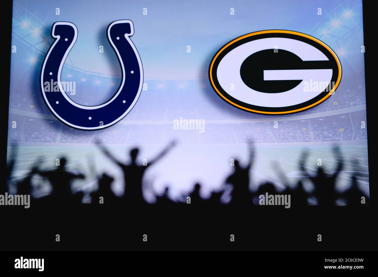 Indianapolis Colts vs. Green Bay Packers. Fans support on NFL Game. Silhouette of supporters, big screen with two rivals in background. Stock Photo