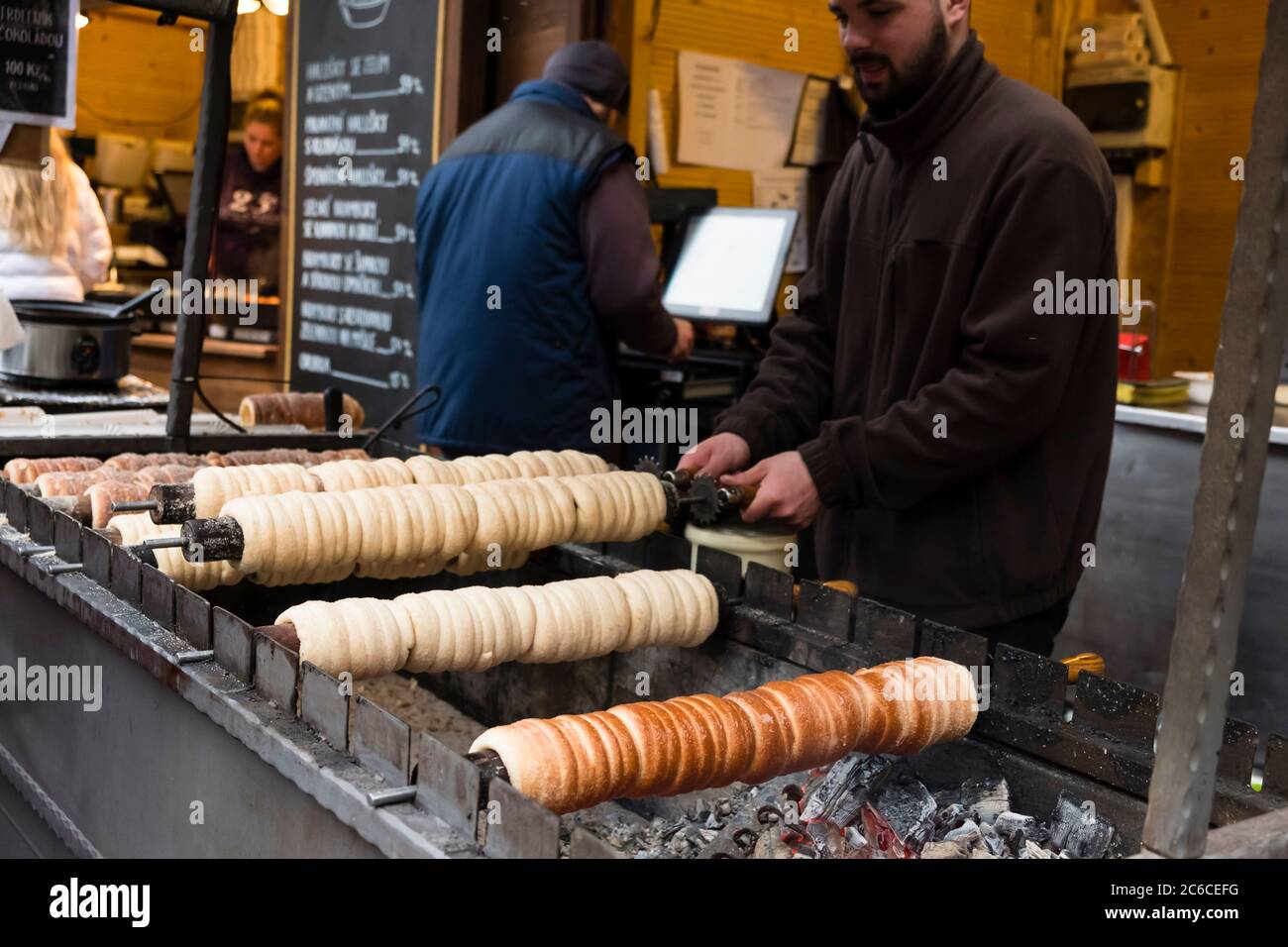 Street food vendors grill Trdelnik, a traditional sweet pastry, at a Christmas market at Prague Castle Stock Photo