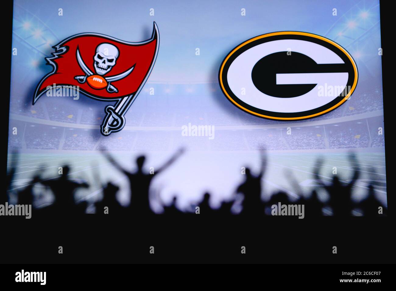 Tampa Bay Buccaneers vs. Green Bay Packers. Fans support on NFL Game. Silhouette of supporters, big screen with two rivals in background. Stock Photo