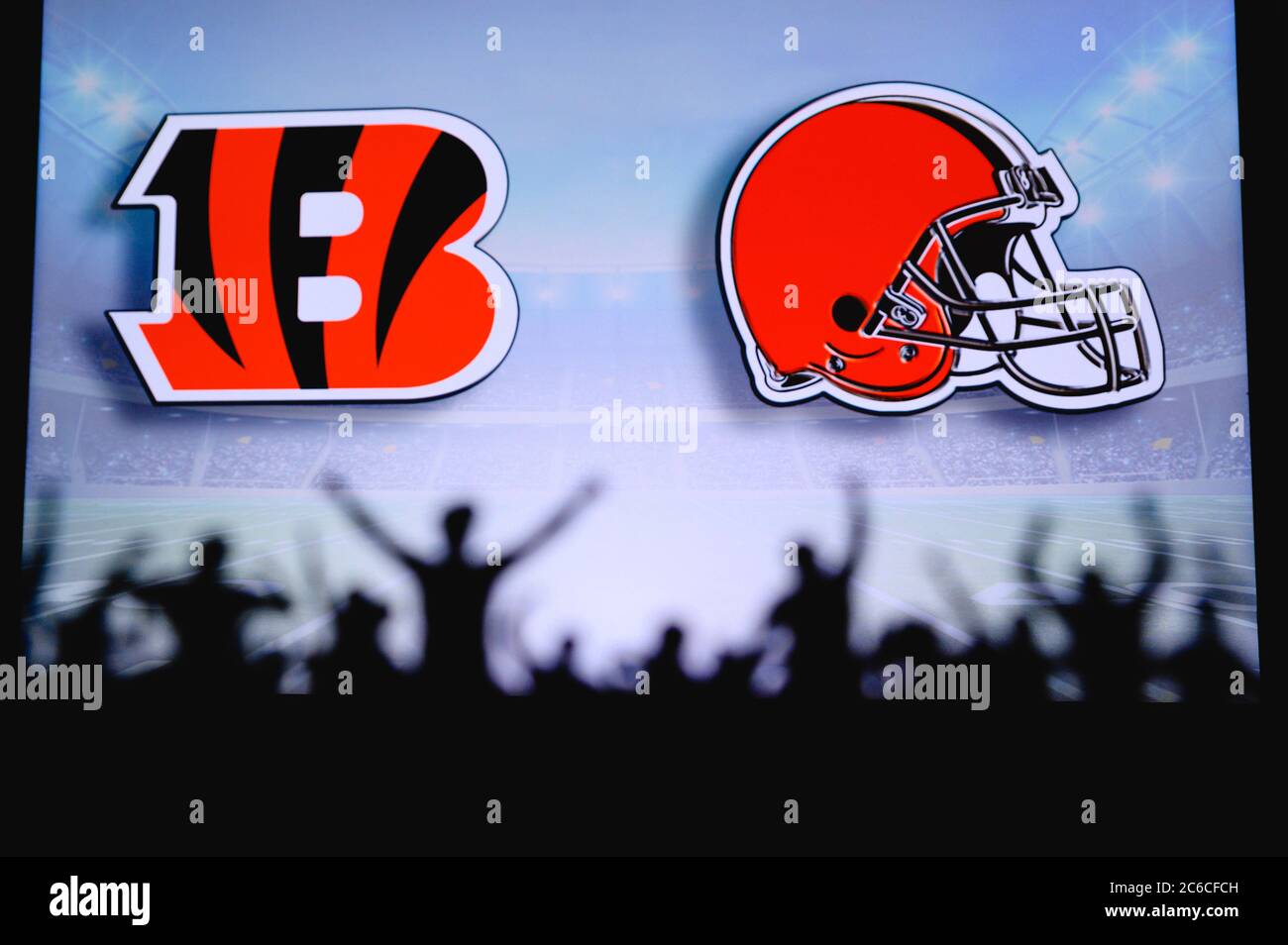 Cincinnati Bengals vs. Cleveland Browns. Fans support on NFL Game. Silhouette of supporters, big screen with two rivals in background. Stock Photo