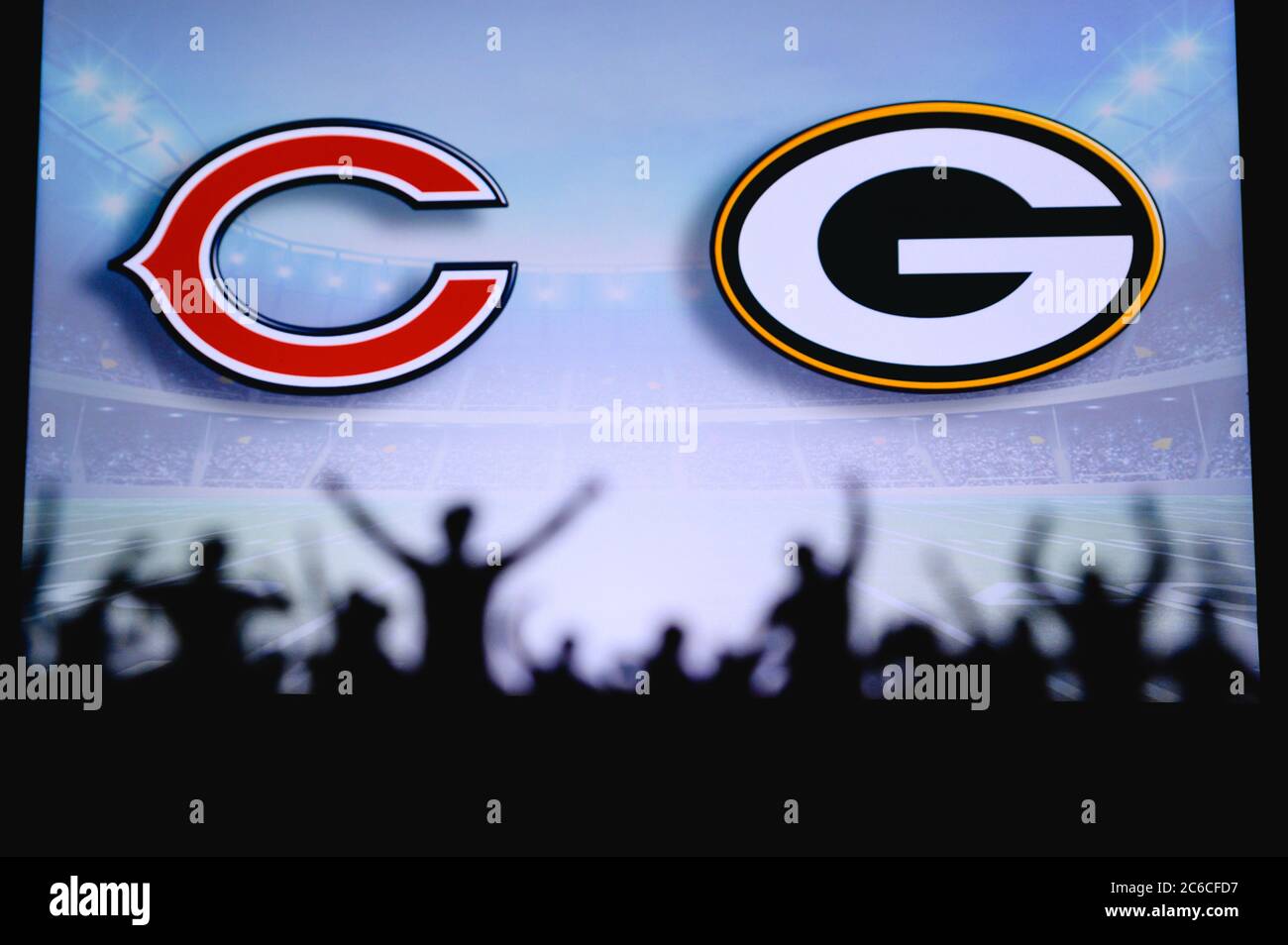 Chicago Bears vs. Green Bay Packers. Fans support on NFL Game. Silhouette of supporters, big screen with two rivals in background. Stock Photo