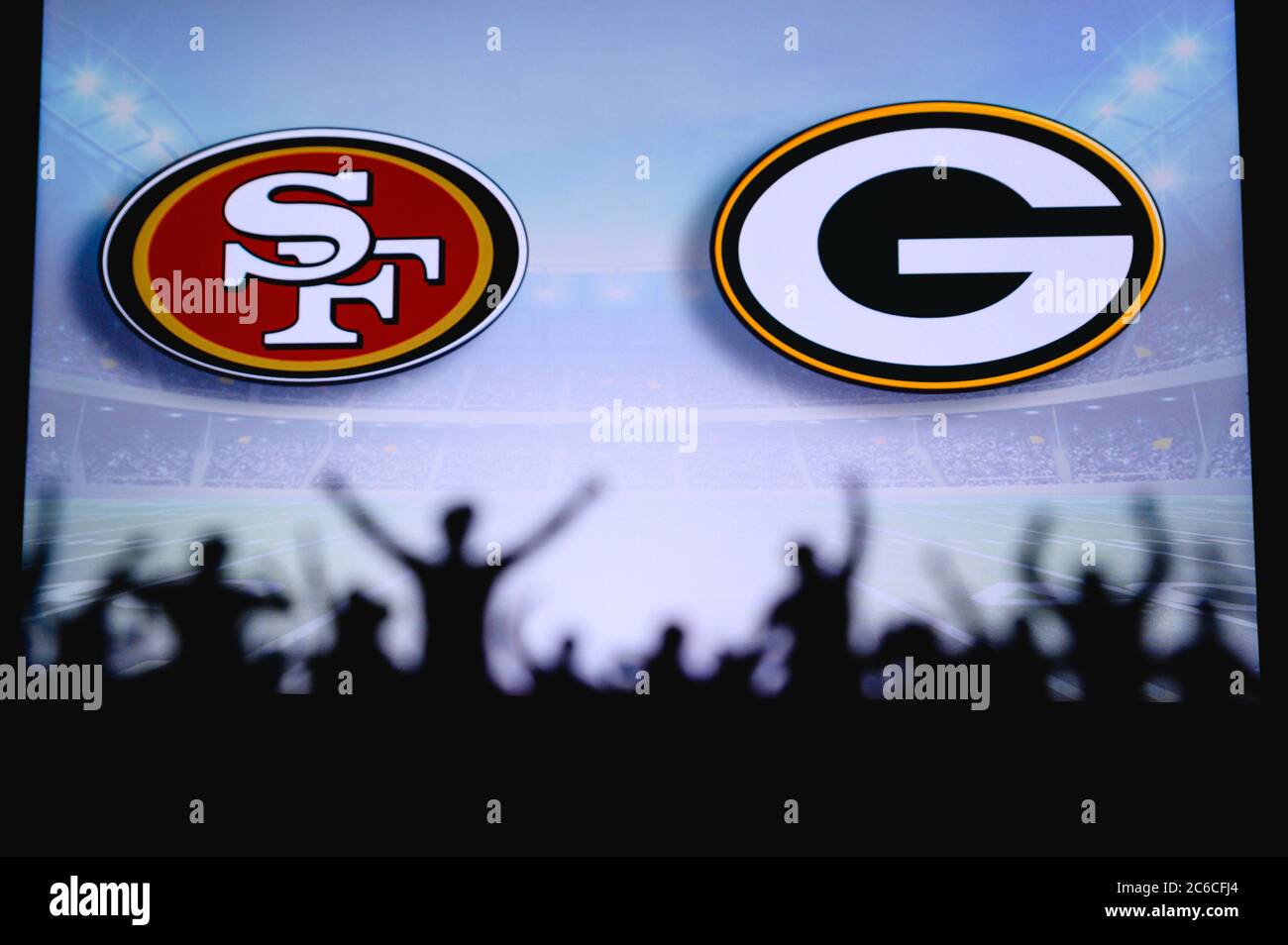 San Francisco 49ers vs. Green Bay Packers. Fans support on NFL Game. Silhouette of supporters, big screen with two rivals in background. Stock Photo