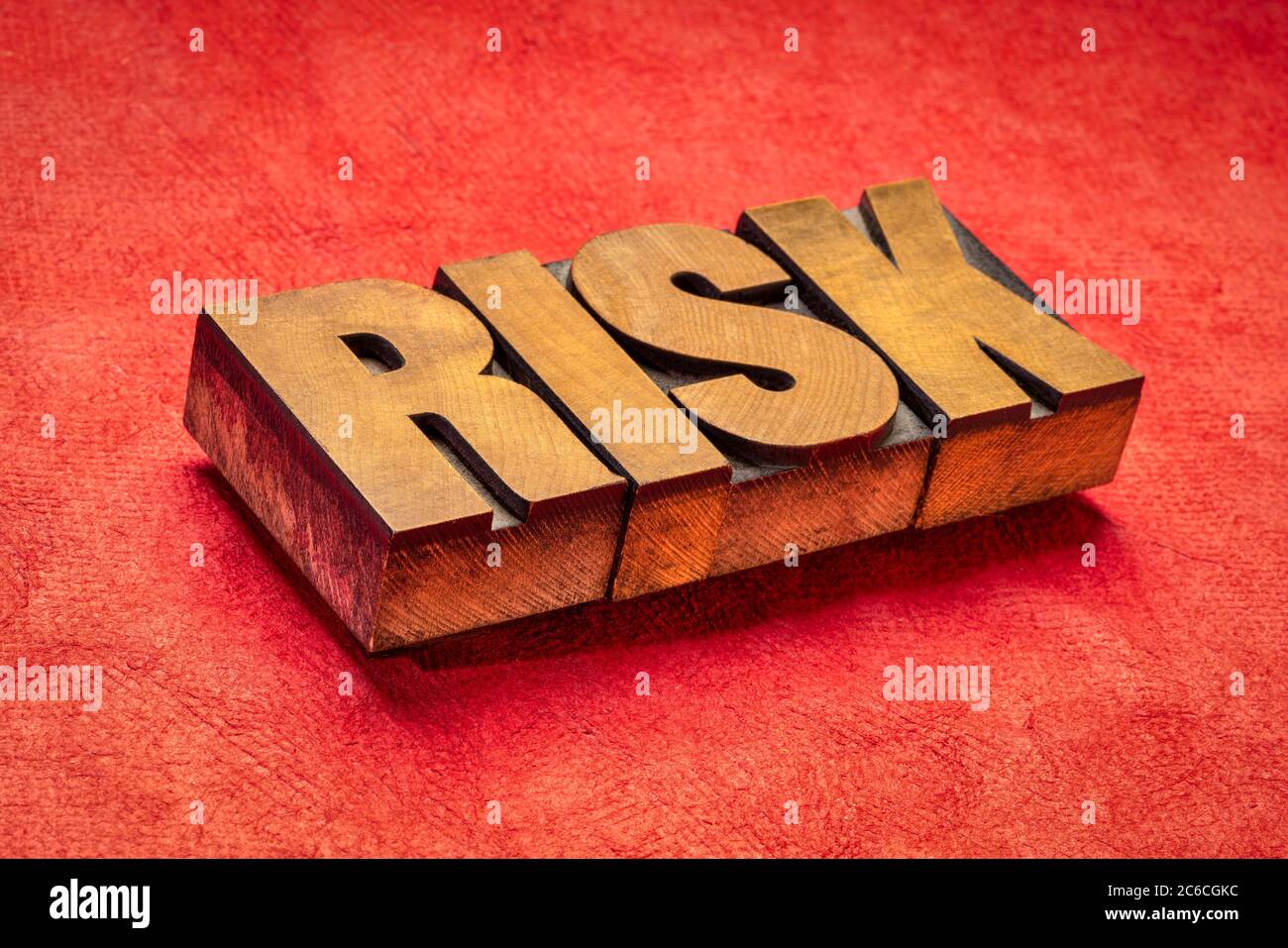 risk word in vintage letterpress wood type against red textured paper, business, danger and uncertainty concept Stock Photo