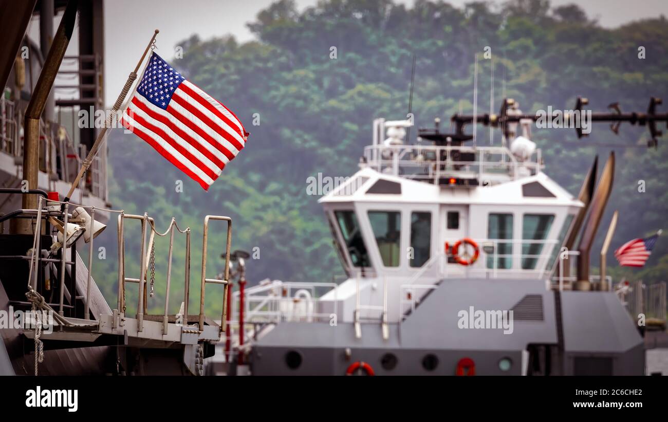 The American flag of a US Navy tugboat as it pushes a ship to its dock in Yokouska, Japan. Stock Photo